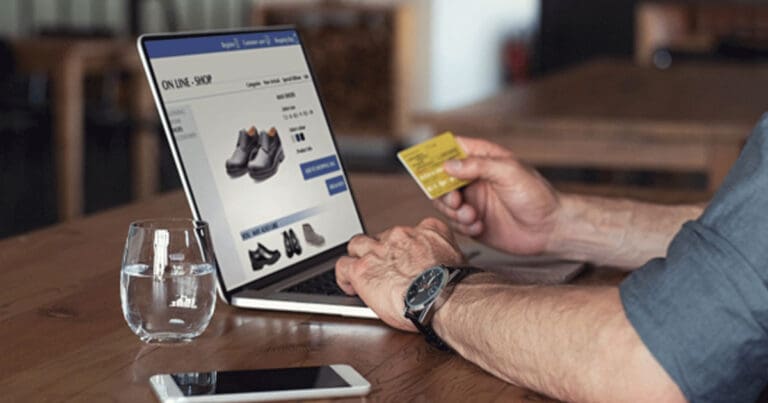 Man holding credit card looking at laptop screen doing online shopping