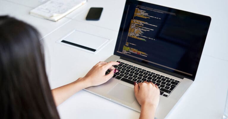 Female programmer writing code at office using laptop