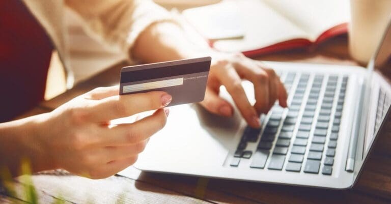 Person holding credit card while online shopping on laptop